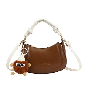 Vintage brown crescent bag with white knot handle and a cute plush monster charm