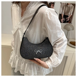 Detail of black glitter crescent underarm bag with silver bow accent on lace shirt