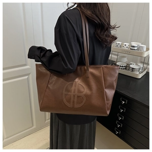 Close-up of deep brown leather tote bag featuring retro lychee texture and embossed logo