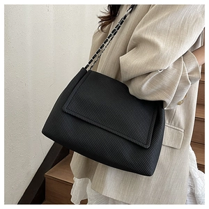 Detail of black twill fabric texture and silver metal chain strap on a tote bag