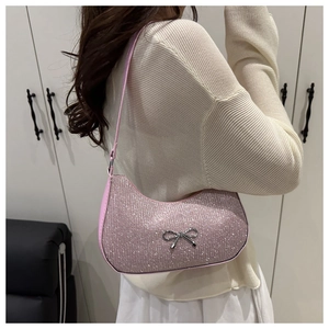 Pink shimmering shoulder bag with silver bow detail worn by a model in soft light