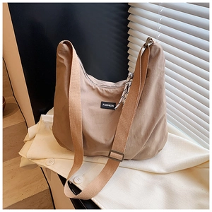 Detail of khaki nylon crescent bag with wide strap, black label, and checkered silk scarf
