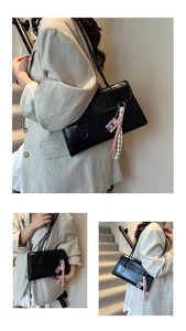 Close-up of black PU leather shoulder bag featuring decorative braided cord and pendant