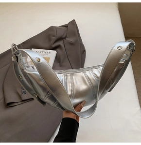 Detail of silver metallic crescent bag featuring vertical pleats and grommet strap