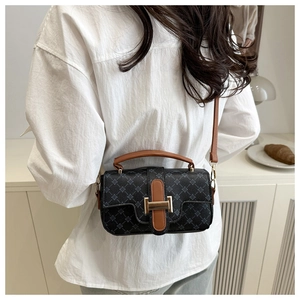 Mannequin portant un sac bandoulière rétro noir à monogramme et boucle dorée élégante