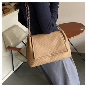 Close-up of brown tote bag with diagonal woven texture and metallic chain shoulder strap