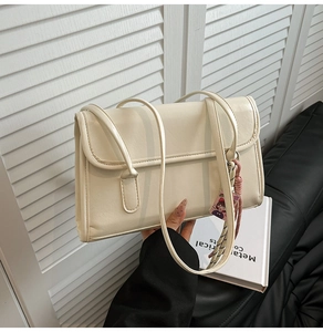 Detail of off-white minimalist shoulder bag with PU leather texture and cute charm pendant