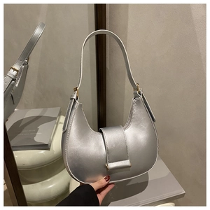 Detail of silver half-moon bag featuring matte metallic finish and golden buckle adjustment