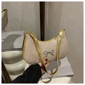 Close-up of champagne glitter shoulder bag featuring a silver bow and metallic trim details