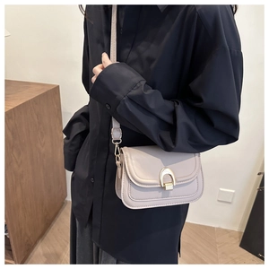 Detail of a beige PU square bag with gold U-shaped buckle and adjustable shoulder strap