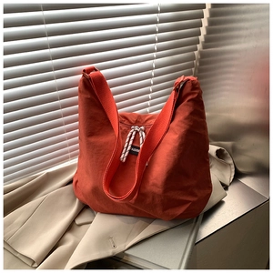 Close-up of deep orange nylon tote bag with Fashion label on brown blazer background