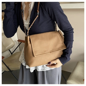 Close-up of the diagonal woven texture and chain strap on a brown tote bag
