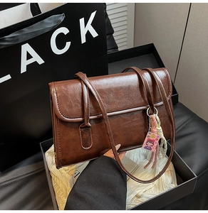 Brown oil wax leather shoulder bag detail with cartoon charm inside a gift box