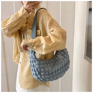 Detail of blue bubble pleated fabric texture on soft crescent-shaped tote shoulder bag