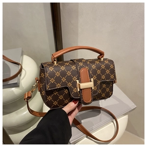 Detail view of the vintage floral pattern and gold clasp on a brown crossbody bag