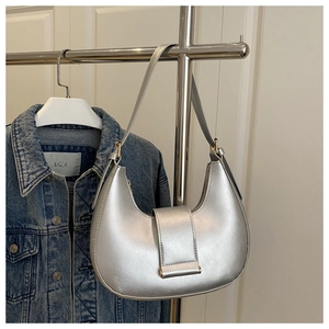 Close-up of silver crescent underarm bag featuring a metallic finish and buckle flap