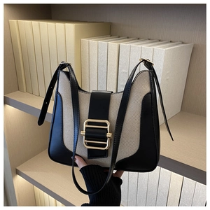 Détail du sac bandoulière en toile beige et cuir noir avec fermoir doré élégant