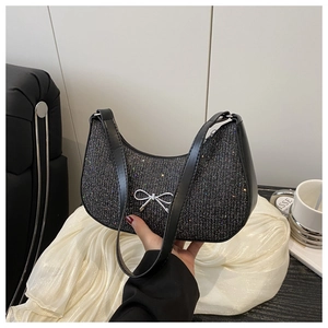 Detail of black sequin hobo bag with silver metallic bow and smooth leather strap