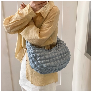 Detailed view of light blue quilted hobo bag with textured bubble fabric on model