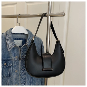 Detail of black faux leather crescent bag with matte finish and gold metal buckle