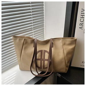 Detail of apricot pleated leather tote bag with brown circular patchwork and thin straps