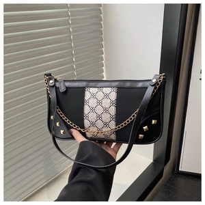 Detail of black baguette bag featuring clover pattern patchwork and gold pyramid studs