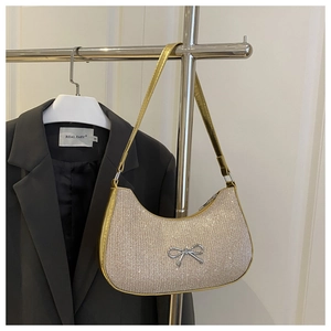 Close-up of golden rhinestone shoulder bag featuring a silver metal bow buckle detail