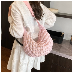 Detail of pink pleated cloud bag with soft texture and wide nylon crossbody strap