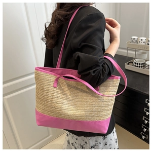 Detail view of large straw tote bag with vibrant magenta straps on female model