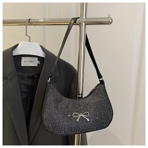 Detail of black glitter crescent bag featuring a silver metal bow clasp and leather strap
