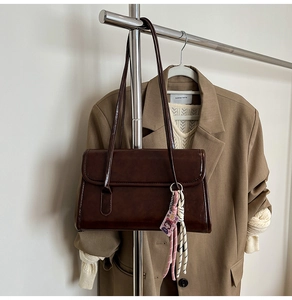 Détail d'un sac à bandoulière marron foncé vintage avec un pendentif en corde tressée