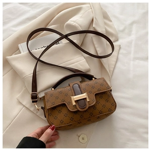 Close-up of a vintage brown patterned crossbody bag with gold hardware on a beige blazer