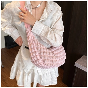 Detail of pink pleated cloud bag featuring textured bubble fabric and wide shoulder strap