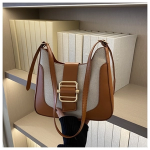 Détail du sac sous le bras en cuir marron et toile avec une boucle en métal doré