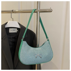 Close-up of a light blue sequin hobo bag with green leather strap and silver bow detail