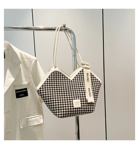 Detail of houndstooth tote bag featuring a V-shaped opening and stylish lettered strap