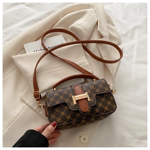 Detail of vintage patterned crossbody bag with brown leather handle and gold hardware