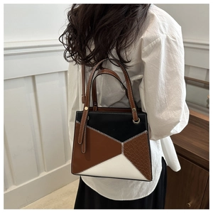 Detailansicht der dreifarbigen Handtasche mit geometrischem Patchwork-Muster an einem Model