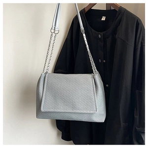 Close-up of light grey textured shoulder bag featuring silver chain strap and flap closure