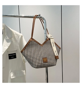 Detail of houndstooth tote bag with brown leather trim and fashion brand tag