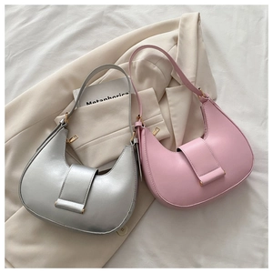 Detail of silver and pink hobo bags with adjustable buckles on soft beige blazer background