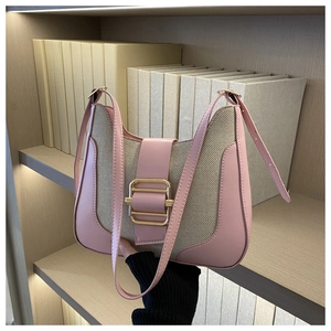 Gros plan du sac en toile rose et beige avec une grande boucle dorée sur une étagère