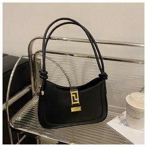 Dettaglio della borsa in pelle nera con fibbia dorata e tracolle con nodo decorativo
