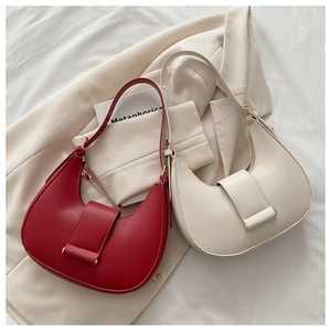 Close-up of hobo bags in red and off-white leather on a beige blazer background