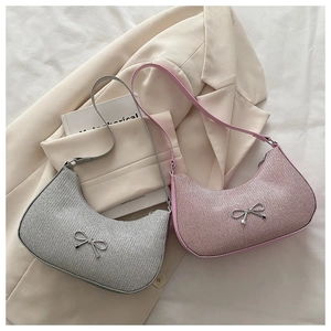 Close-up of silver and pink sequined hobo bags with metallic bow detail on white fabric