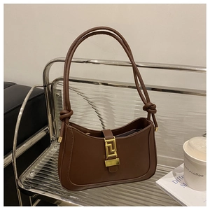 Dettaglio borsa a mezzaluna marrone scuro con fibbia dorata e tracolla con nodo decorativo