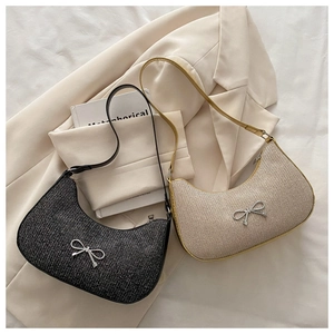 Detail showing woven texture and glitter material of shoulder bags with metal bow