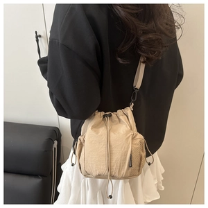Vue de dos d'un sac seau beige en nylon avec poche latérale en filet et sangle réglable