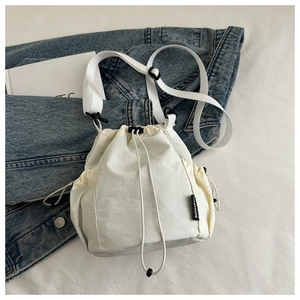 Detailansicht der cremefarbenen Nylon-Beuteltasche mit Netzfach und Fashion-Label