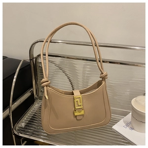 Dettaglio borsa a mezzaluna beige con fibbia dorata a chiave greca e manico in corda annodata